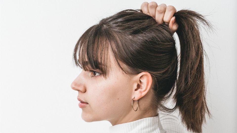 Para evitar que el sudor entre en contacto con tu cabello, un método útil es atarlo.